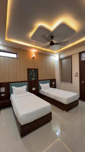 a bedroom with two beds and a ceiling at Hotel Abhinandan Palace in Udaipur