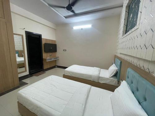 a room with two beds and a tv in it at Hotel Abhinandan Palace in Udaipur
