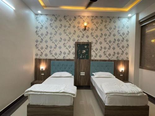 two twin beds in a room with wallpaper at Hotel Abhinandan Palace in Udaipur