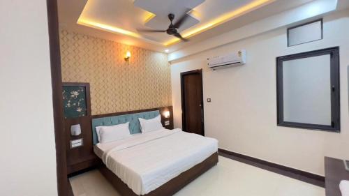 a bedroom with a white bed with a ceiling fan at Hotel Abhinandan Palace in Udaipur