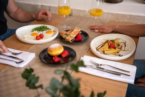 a table with plates of breakfast food and glasses of orange juice at Hotel Marina in Fažana