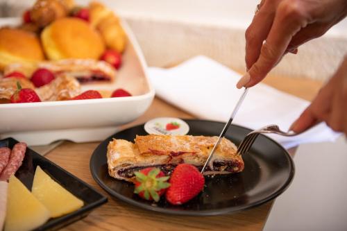 a person eating a piece of food on a plate with strawberries at Hotel Marina in Fažana