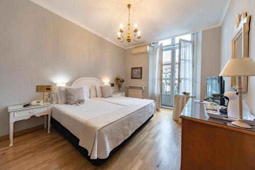 Infanta Isabel by Recordis Hotels في سيغوفيا: غرفة نوم بسرير ابيض كبير وتلفزيون