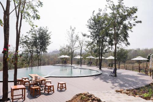 una piscina con tavoli, sedie e alberi di Happiness Long Bridge Resort 