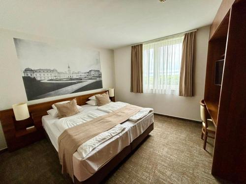 a bedroom with a large bed with a painting on the wall at Zenit Wellness Hotel Balaton in Vonyarcvashegy