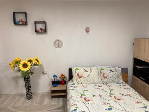 1 dormitorio con 1 cama y un jarrón con flores en Cosy Hideaway, en Brasov