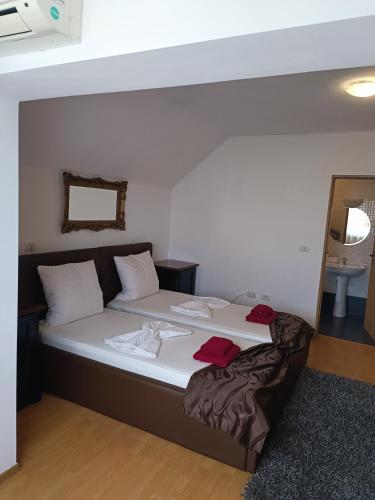 a bed with white sheets and red towels on it at Family Pension in Arad