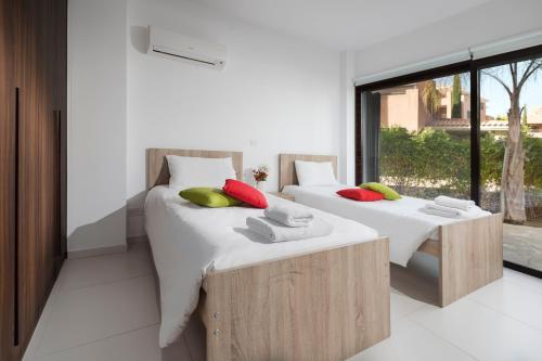 two twin beds in a room with a window at Resitour - Aphrodite Gardens in Paphos City