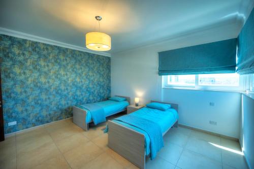 two beds in a room with blue walls at Fort Cambridge Apartments in Sliema