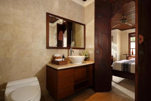 a bathroom with a sink and a toilet and a bed at Jimbaran Beach Villas by Nakula in Jimbaran