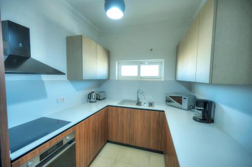 a kitchen with white counter tops and wooden cabinets at Fort Cambridge Apartments in Sliema