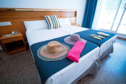a hotel room with a bed with hats and towels at Hotel - Bungalows Don Juan Tossa in Tossa de Mar