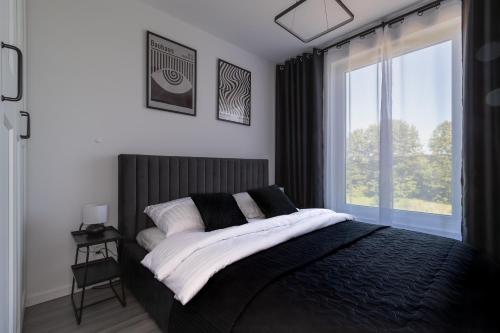 a bedroom with a black and white bed and a window at Glow Apartments, Letnica - Apartamenty Bursztynowa Zatoka&Przystań Letnica in Gdańsk