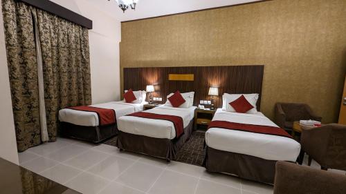 a hotel room with three beds and a desk at City Tower Hotel in Fujairah