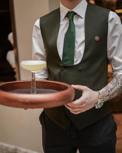 a man in a green vest and tie holding a bowl at Sanasaryan Han, a Luxury Collection Hotel, Istanbul in Istanbul