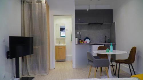 - un salon avec une cuisine et une table avec des chaises dans l'établissement charming studio saint martin, à Pontoise