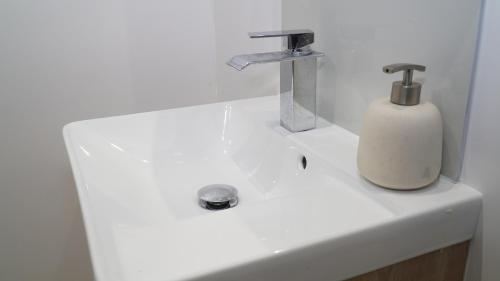 - un lavabo blanc dans la salle de bains avec un distributeur de savon dans l'établissement charming studio saint martin, à Pontoise