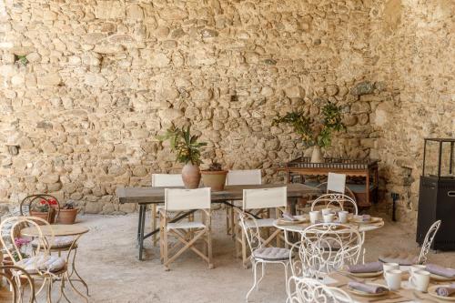 a room with a table and chairs and a stone wall at Castell de Vallgornera in Girona