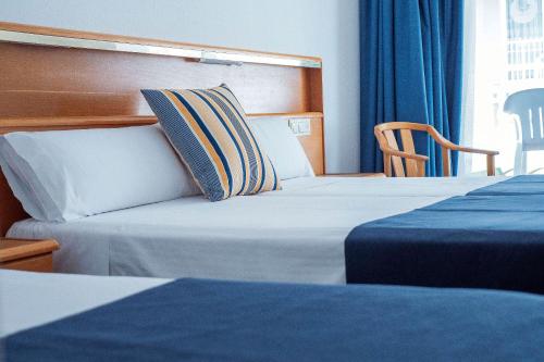 une chambre d'hôtel avec deux lits et une chaise dans l'établissement Hotel - Bungalows Don Juan Tossa, à Tossa de Mar
