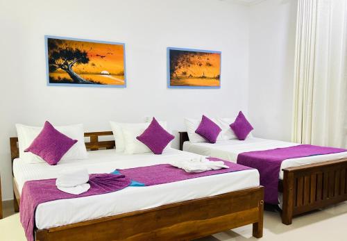 Lake Face Hotel في أنورادابورا: سريرين في غرفة ذات أغطية أرجوانية