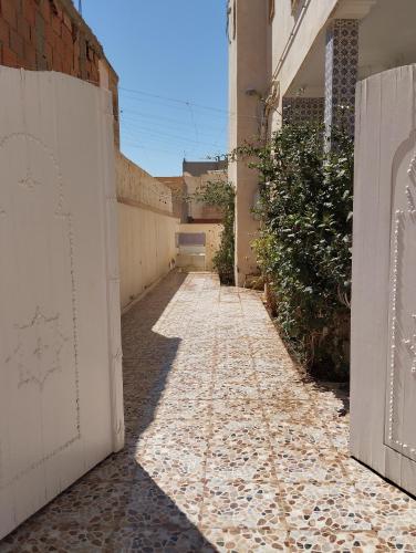 an alley with a white fence and a brick wall at Dar Ezzahra in Tozeur