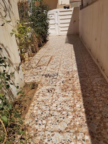 a stone walkway with a white door and a gate at Dar Ezzahra in Tozeur