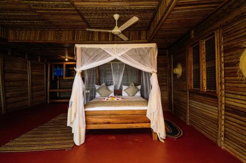 uma cama num quarto com uma ventoinha de tecto em Maisara Mafia Beach Lodge em Kilindoni
