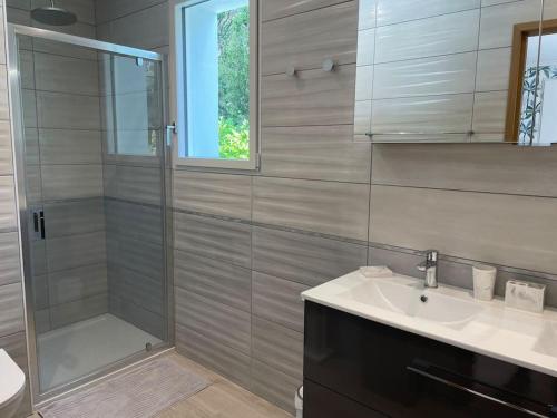 une salle de bain avec une douche, un lavabo et un miroir dans l'établissement Briseis, maison d'architecte proche de la mer, à Sainte-Marguerite