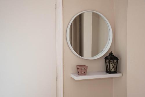 a mirror on a wall with a shelf and a lamp at Amalia Complex in Nisakion