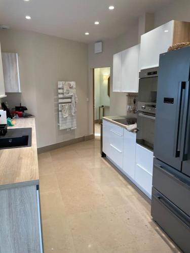 une grande cuisine avec des armoires et des appareils blancs dans l'établissement Briseis, maison d'architecte proche de la mer, à Sainte-Marguerite