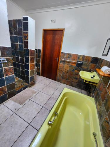 a bathroom with a green tub and a sink at Pine Valley in Lanseria