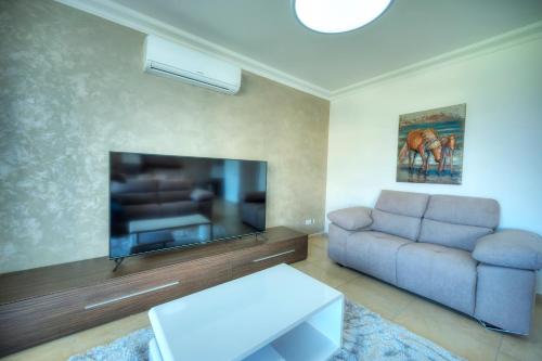 a living room with a couch and a flat screen tv at Fort Cambridge Apartments in Sliema