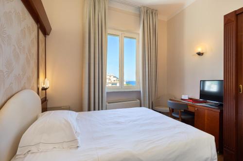 a hotel room with a bed and a television at Grand Hotel Mediterranee in Alassio