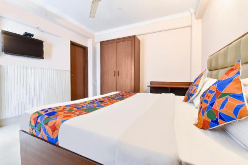 a bedroom with a large white bed with colorful pillows at FabExpress Central Plaza in Dehradun