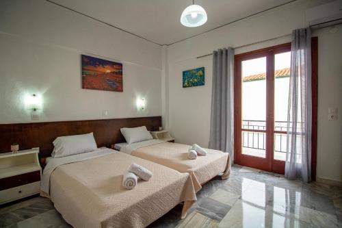two beds in a room with a window at Harry's Bar & Apartments 1 in Acharavi