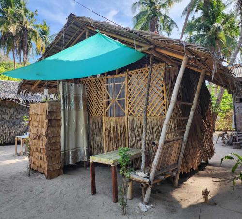 uma cabana com um banco e um guarda-chuva azul em Bice Camp Darocotan em El Nido