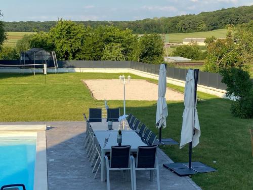uma mesa com cadeiras e guarda-sóis ao lado de uma piscina em Domaine Bienvenue à la Saône em Montureux-lès-Baulay