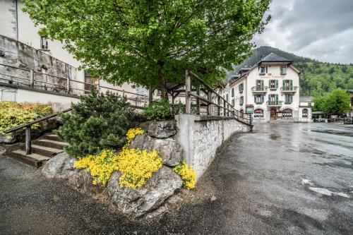 a building with a tree and flowers on a rock at L' Abbaye in Abondance