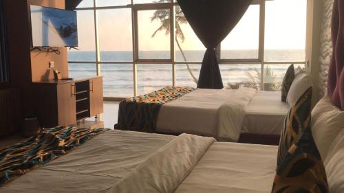 two beds in a room with a view of the ocean at Aryana Queen Beach Resort in Wadduwa