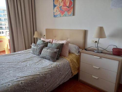 a bedroom with a bed with pillows and a dresser at Beachfront apartment DIANA 2 in Benalmádena