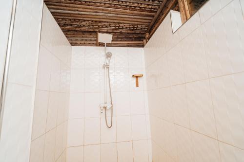 a shower in a bathroom with white tiles at Maisara Mafia Beach Lodge in Kilindoni