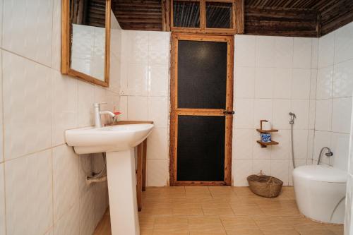 a bathroom with a sink and a toilet and a door at Maisara Mafia Beach Lodge in Kilindoni