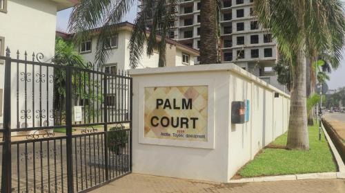 a sign on a fence in front of a building at Palm Court Apartment in Accra