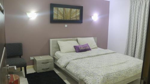 a bedroom with a bed with a purple pillow on it at Palm Court Apartment in Accra