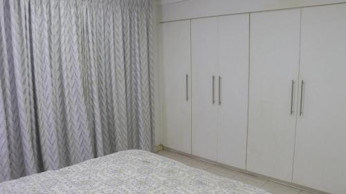 a bedroom with white cabinets and a bed at Palm Court Apartment in Accra