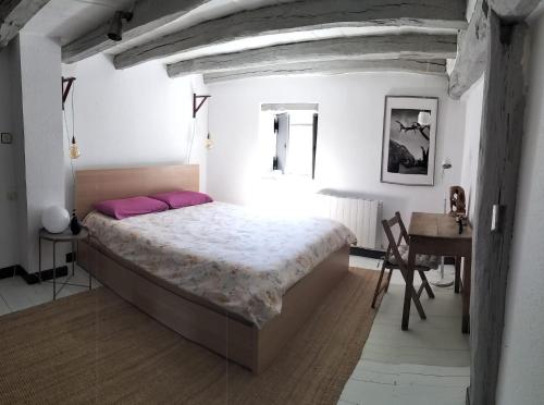 - une chambre avec un lit avec des oreillers roses et un bureau dans l'établissement Casa tradicional en Orozko, à Murueta-Orozko