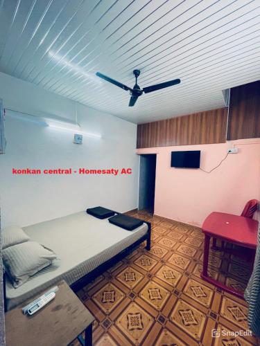 a room with a bed and a ceiling fan at Konkan Central Kankavali - Home Stay in Kankauli