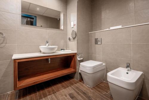 a bathroom with a sink and a toilet and a mirror at Vivaldi Hotel in St Julian's