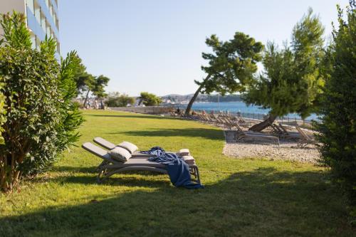 a bench sitting on the grass near the water at Villa Arausa in Vodice