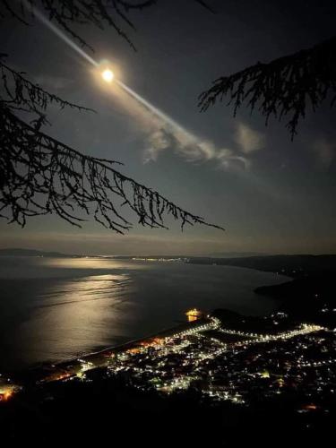 a moonlit view of a city and the ocean at night at ANASTASIA ROOMS in Stratónion